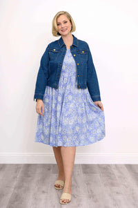 Woman wearing a blue floral dress styled with a denim jacket and beige sandals