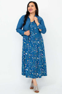 Woman looking sideways in blue floral maxi dress layered with denim jacket