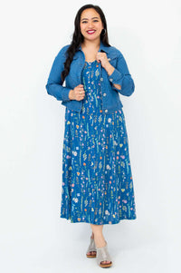 Woman wearing a blue floral maxi dress layered with a denim jacket