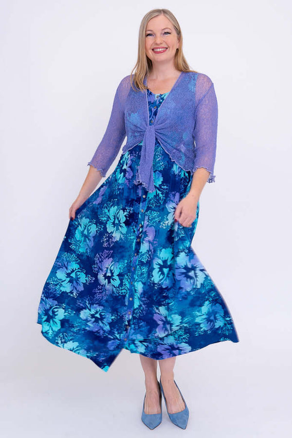 Woman in blue floral maxi dress with a sheer purple tie-front cardigan, twirling the skirt