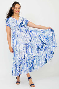 Woman holding out the skirt of a blue paisley maxi dress, showcasing its volume