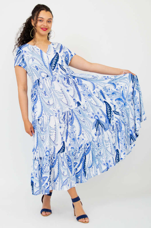 Woman holding out the skirt of a blue paisley maxi dress, showcasing its volume