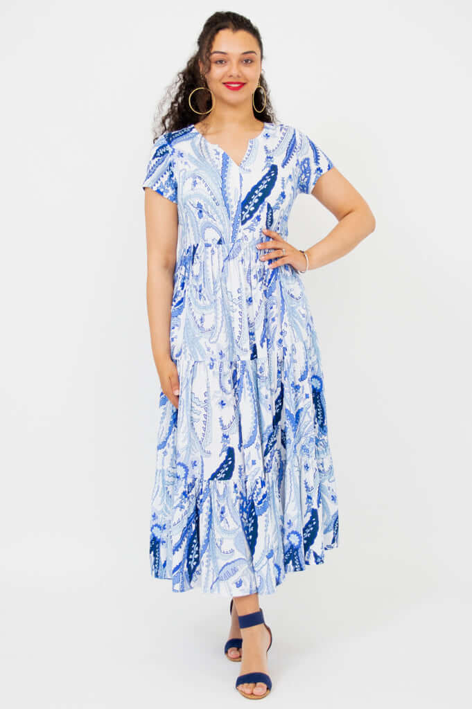 Woman wearing a blue paisley short sleeve maxi dress, standing and smiling
