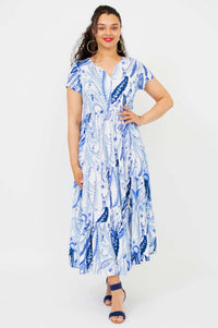 Woman wearing a blue paisley short sleeve maxi dress, standing and smiling