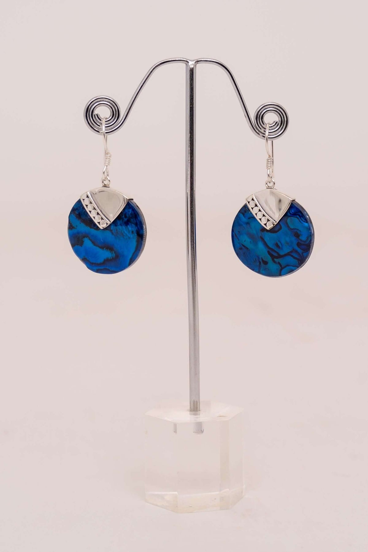 Pair of blue round drop earrings with sterling silver accents displayed on a stand