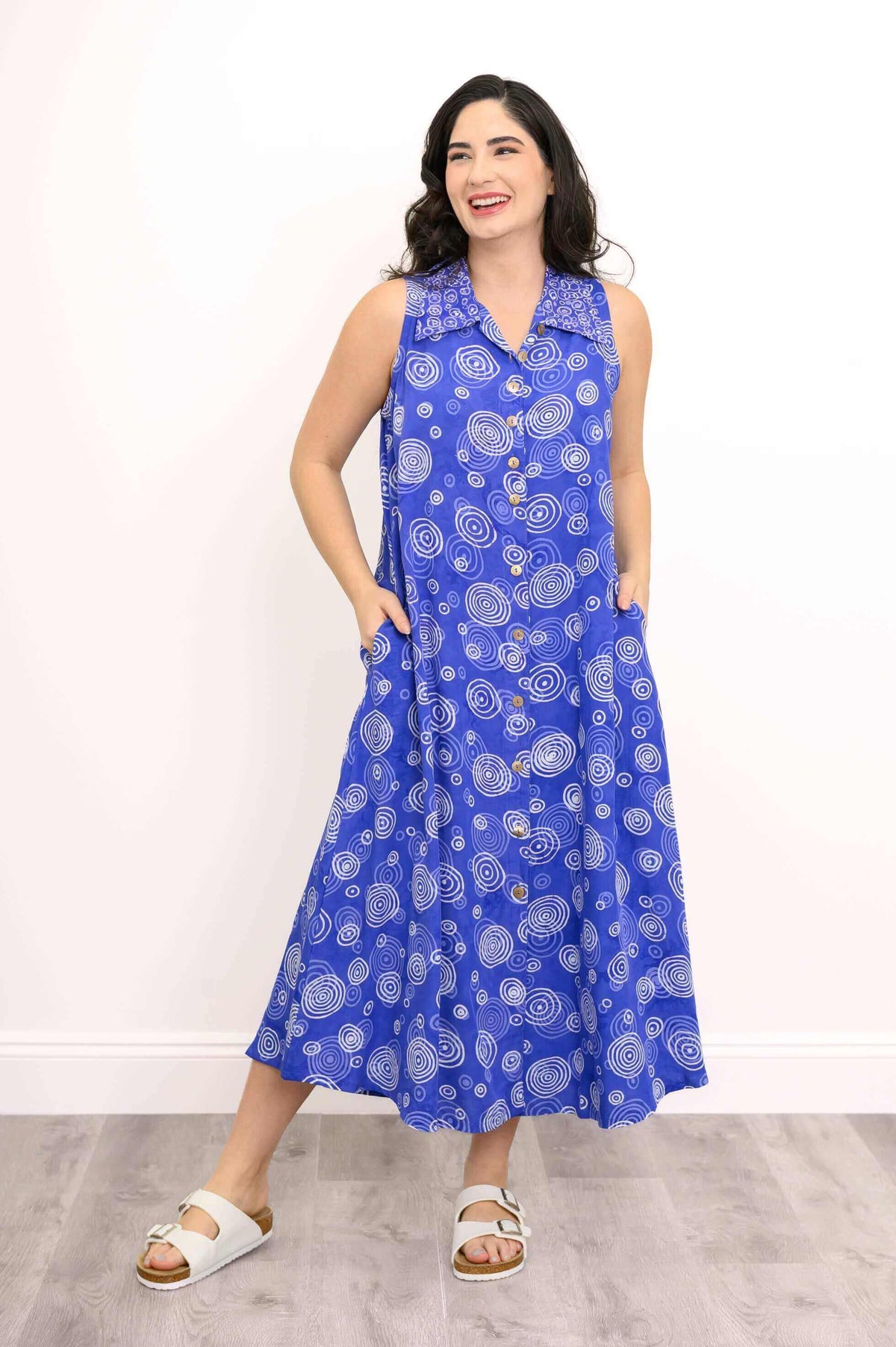 Model showcasing blue swirl button-up dress with hands in pockets