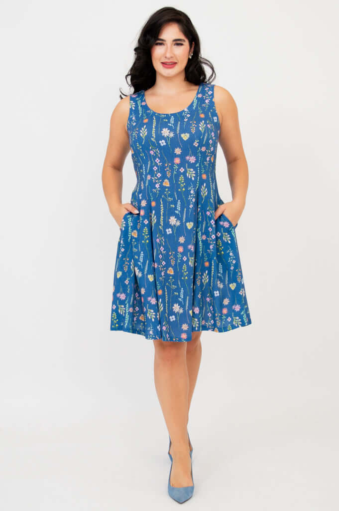 Front view of woman wearing blue sleeveless floral A-line summer dress with pockets