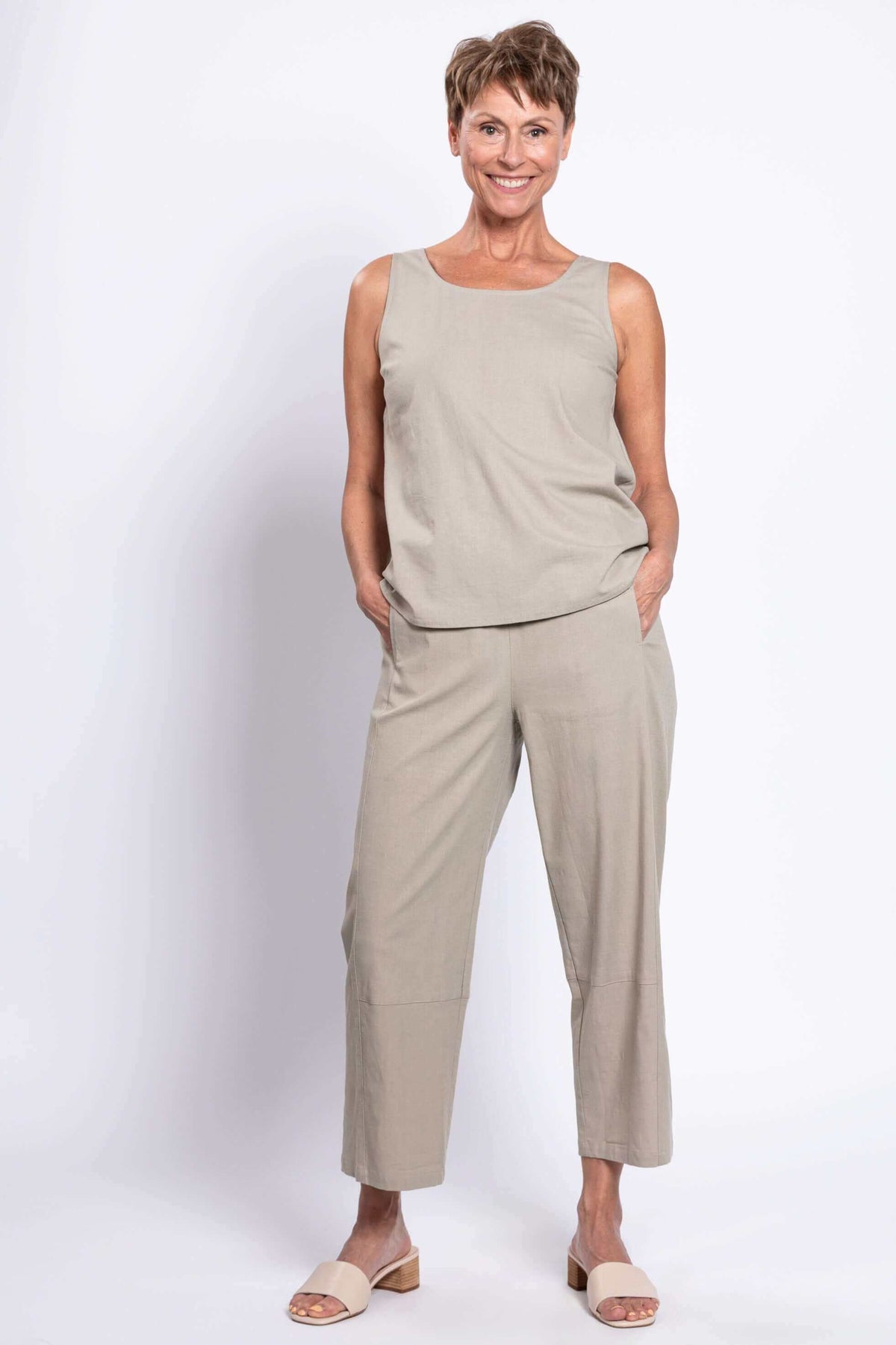 Woman wearing light beige sleeveless top and barrel-leg cropped pants set, front view, hands in pockets
