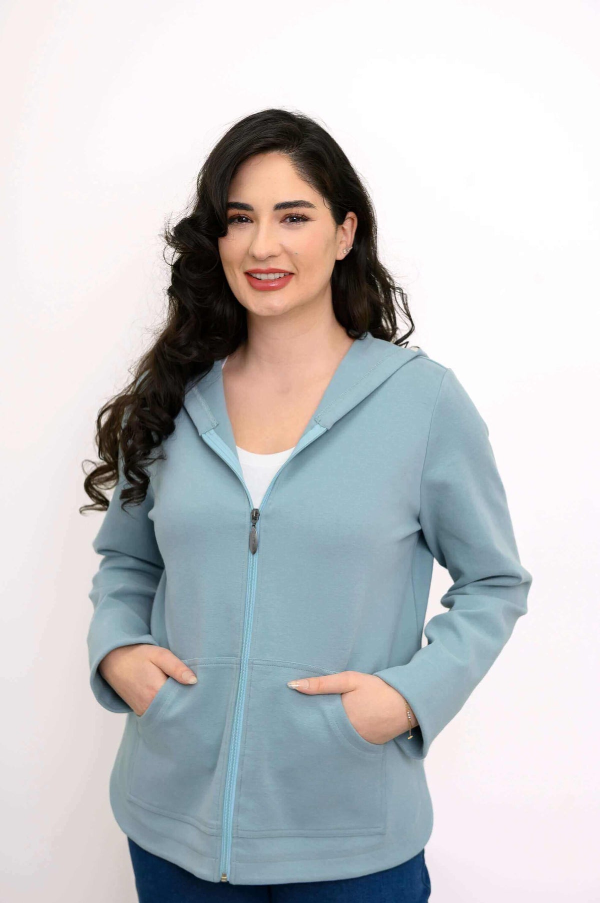 Woman posing in a light blue zip-up hoodie jacket, hands in pockets