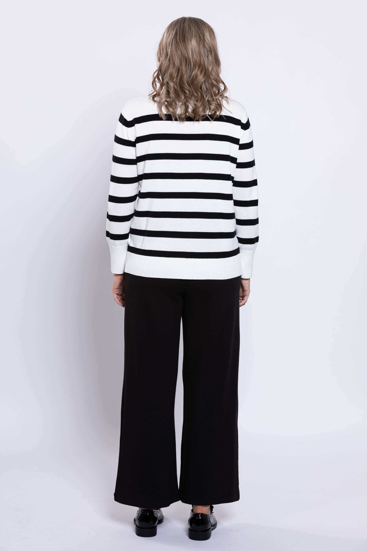 Back view of woman wearing a Breton stripe V-neck sweater, showing ribbed hem and cuffs