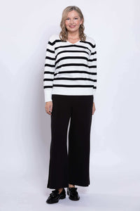 Front view of woman standing in black and white striped V-neck sweater with relaxed fit