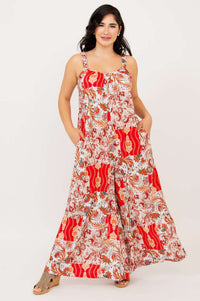 Woman posing with hands in pockets wearing a bright red patterned jumpsuit