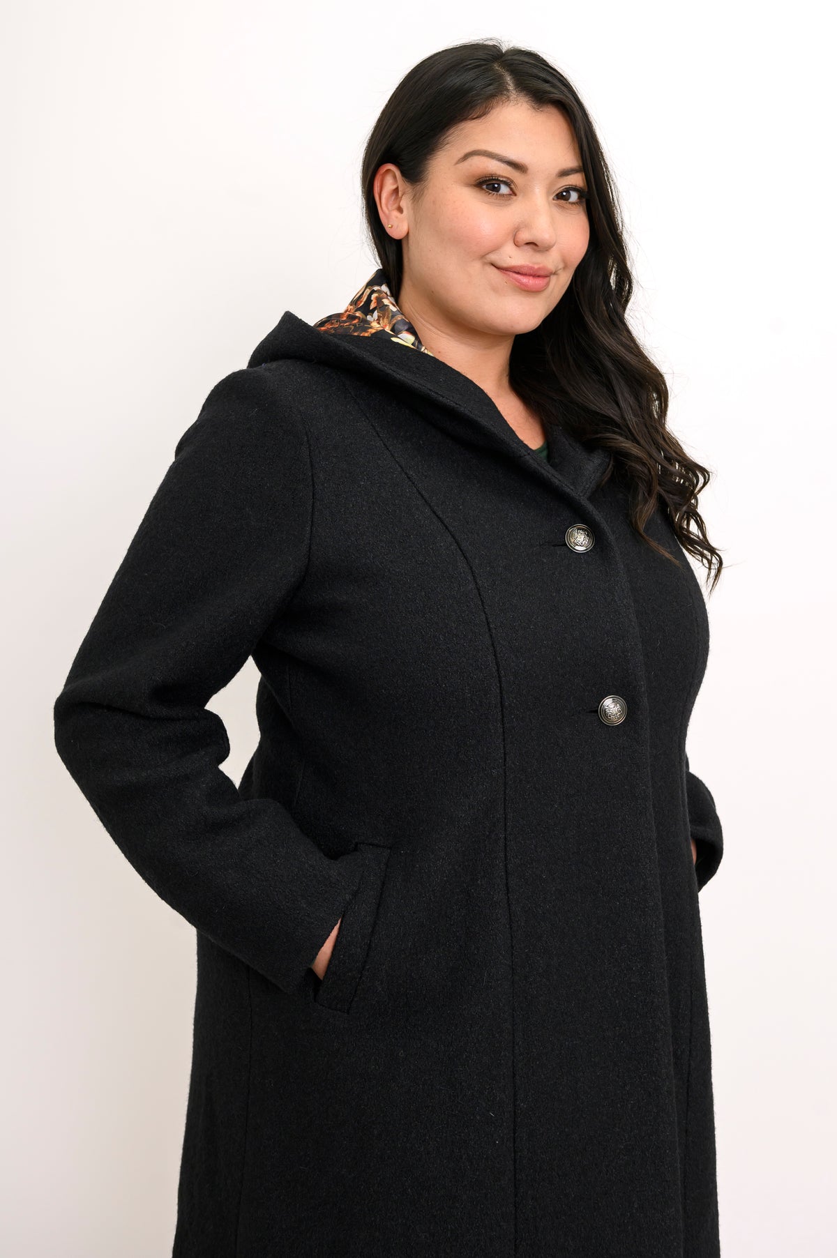 Close-up side view of woman wearing black boiled wool coat with pockets and silver buttons