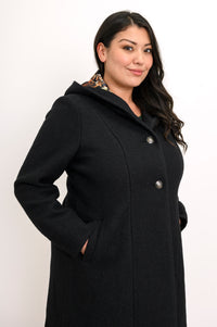 Close-up side view of woman wearing black boiled wool coat with pockets and silver buttons