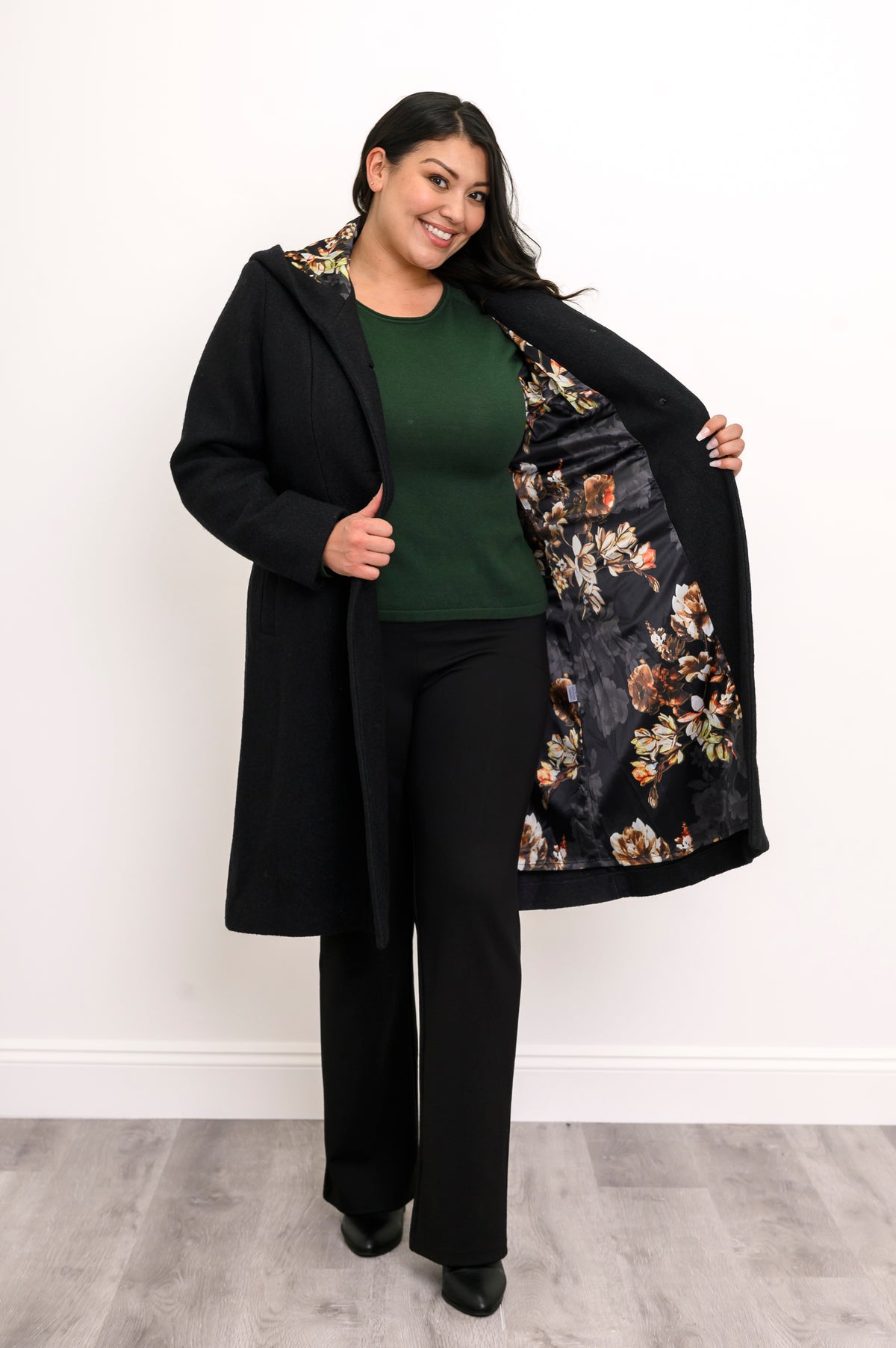 Woman showing off the black and multicolor floral satin lining of her long black coat