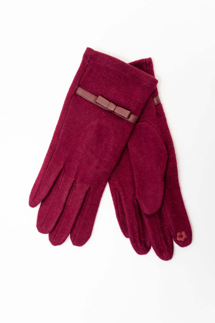 Pair of burgundy wool gloves with a brown bow accent on a white background