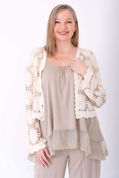 Woman displaying button-up crocheted cardigan with open front over neutral layered outfit