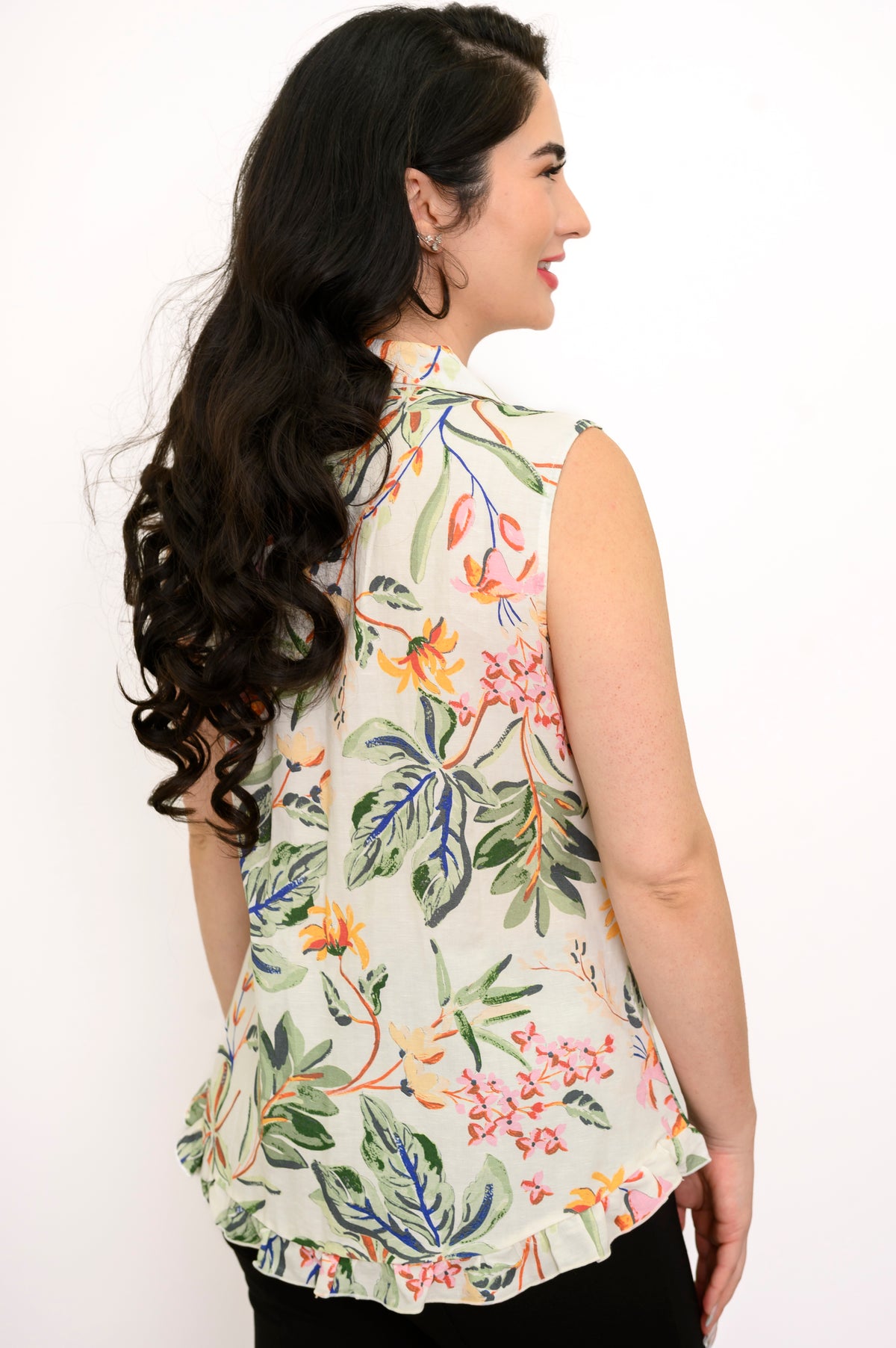 Back view woman wearing multicolor tropical print sleeveless top with green pants on a white background