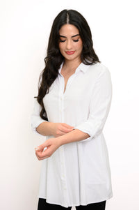 Woman touching the sleeve of her white collared-button up blouse against a white background