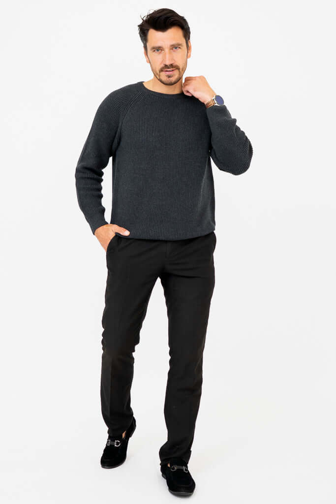 Man modeling a charcoal ribbed sweater and black pants, hand on neck