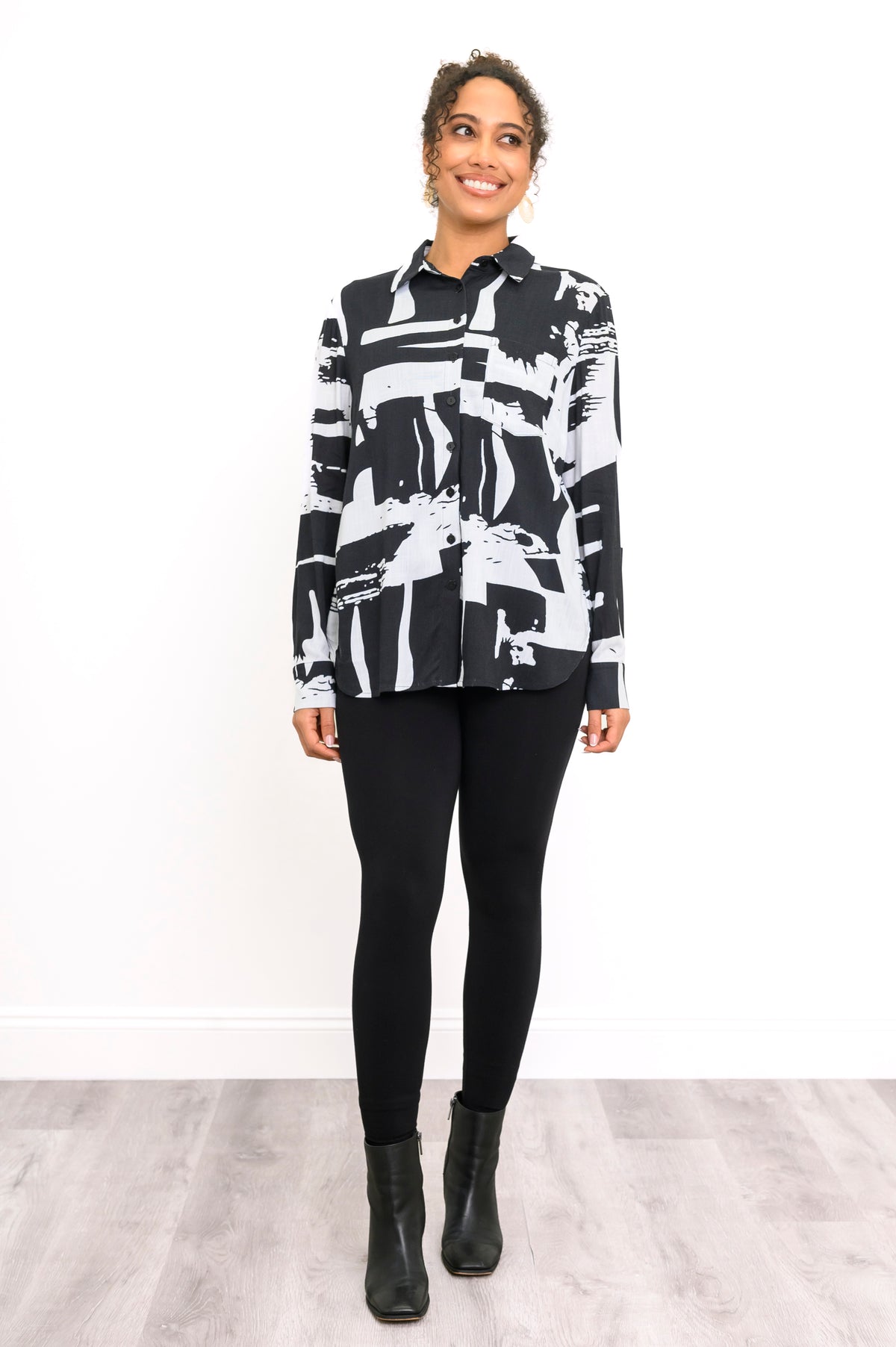 Straight-on full body portrait of a women's patterned black and white long-sleeve shirt worn open as a light jacket