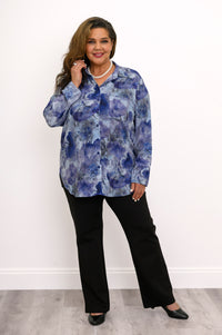 Wide studio shot of a loose-fit blue floral linen bamboo blend shirt styled with black pants and heels.