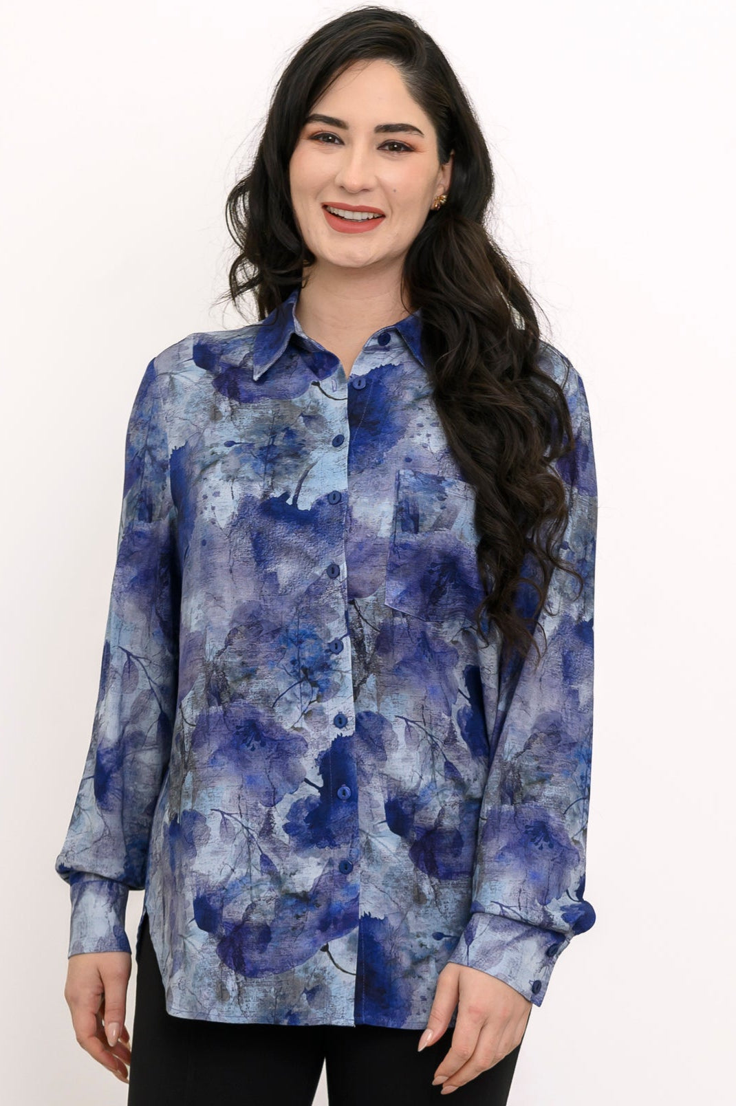 Front view of a smiling woman in a blue watercolor print button-down shirt with a spread collar.