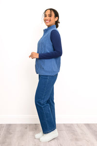 Angled view of an indigo knit layering vest, showcasing a comfortable, body-skimming fit on a model.