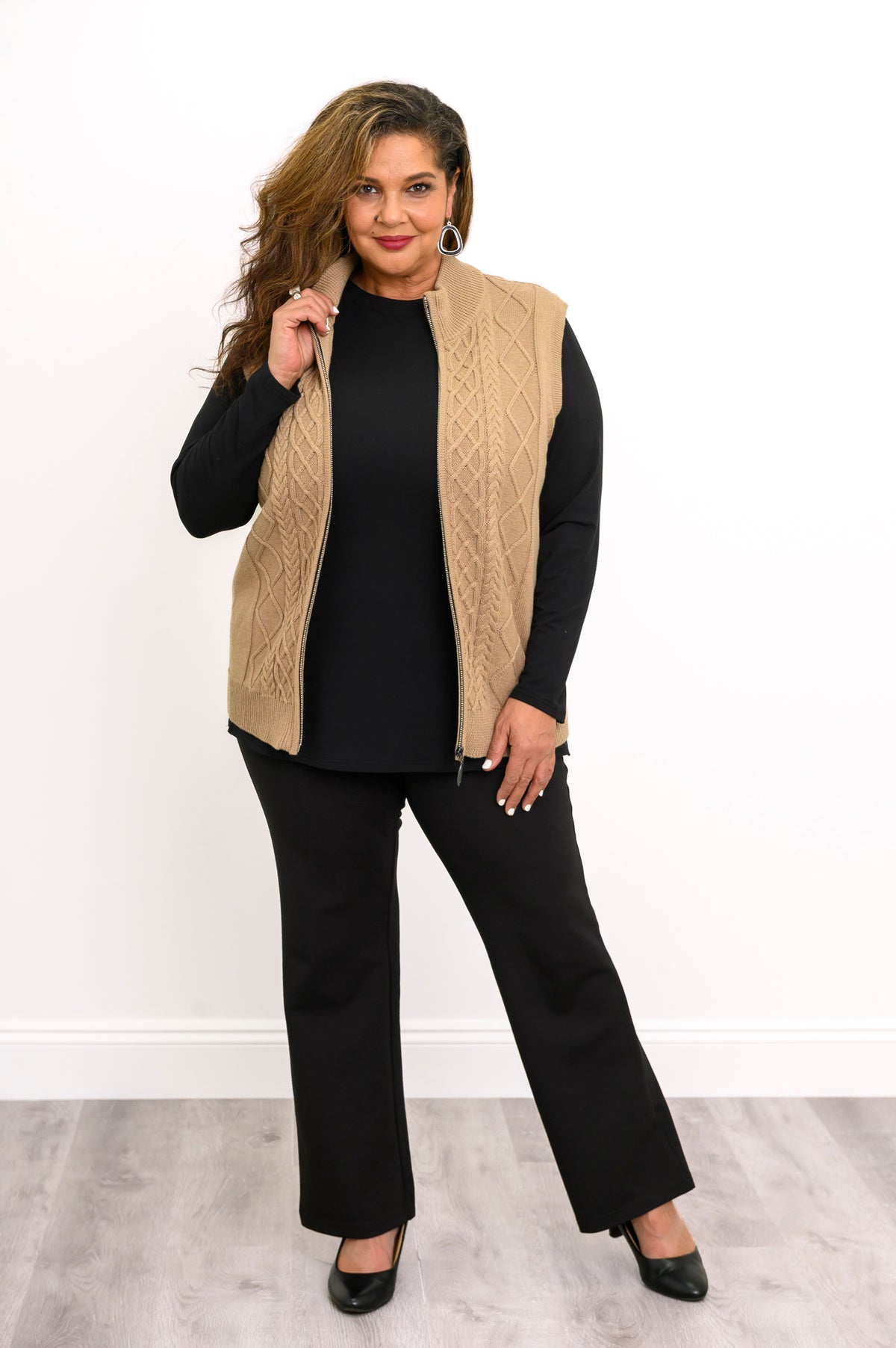 Front-facing view of a women's neutral-toned zip-up layering vest and black pants, showcasing a relaxed fit.