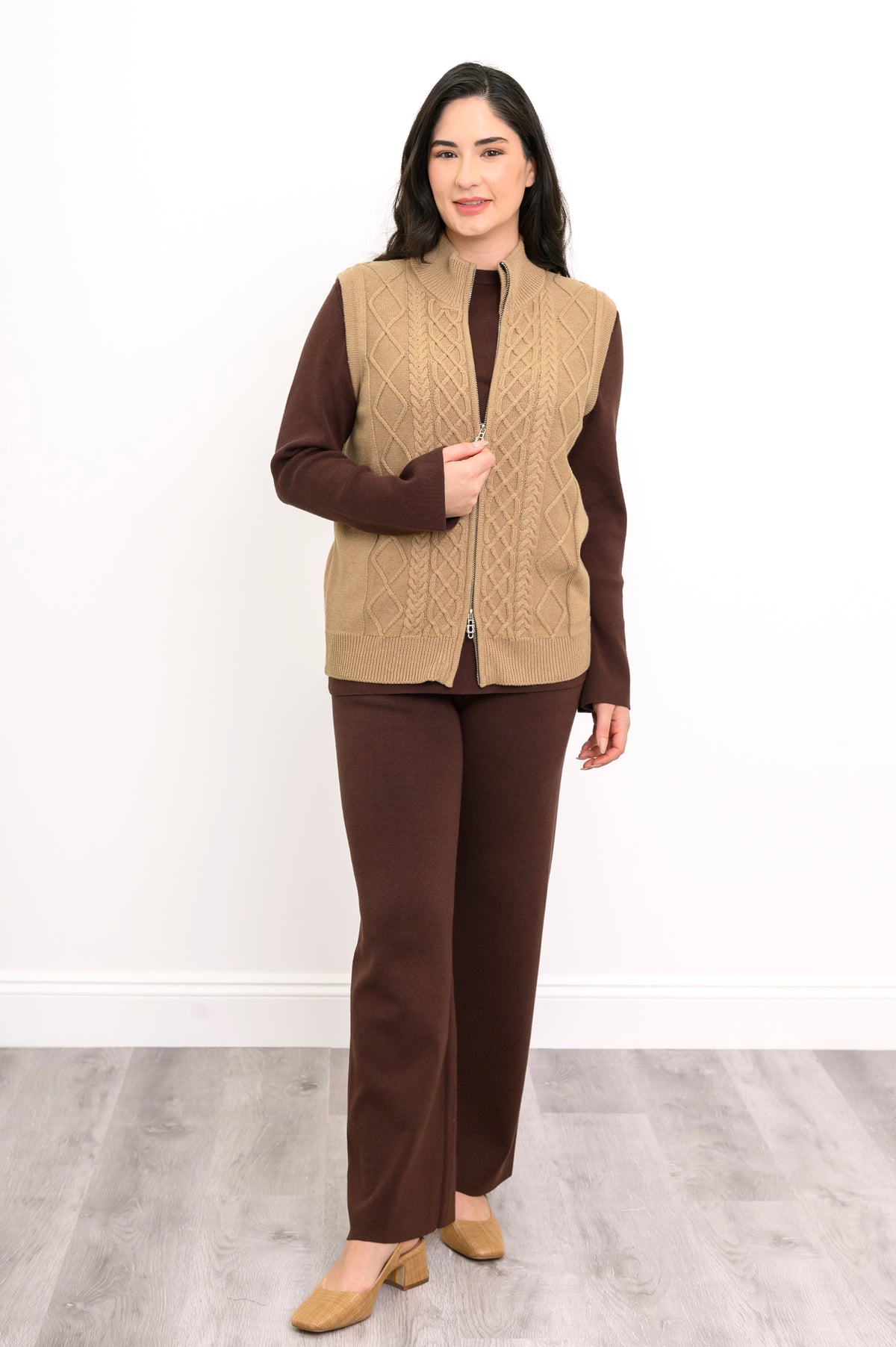 Sleeveless cotton sweater vest with vertical cabling and silver-colored zippers, shown from an active side angle