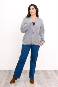 front view of woman posing in grey sweater, straight leg jeans, and brown boots