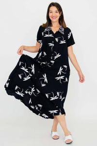Woman in black and white floral A-line dress holding out the skirt to show its swing and movement