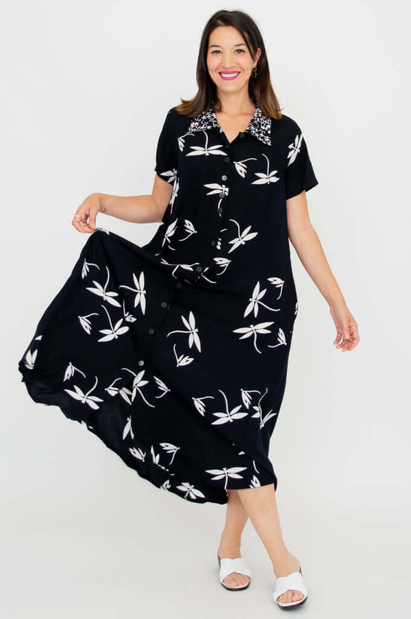 Woman in black and white floral A-line dress holding out the skirt to show its swing and movement