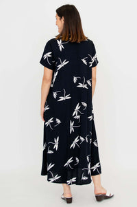 Back view of black A-line dress with white floral prints, worn by a woman