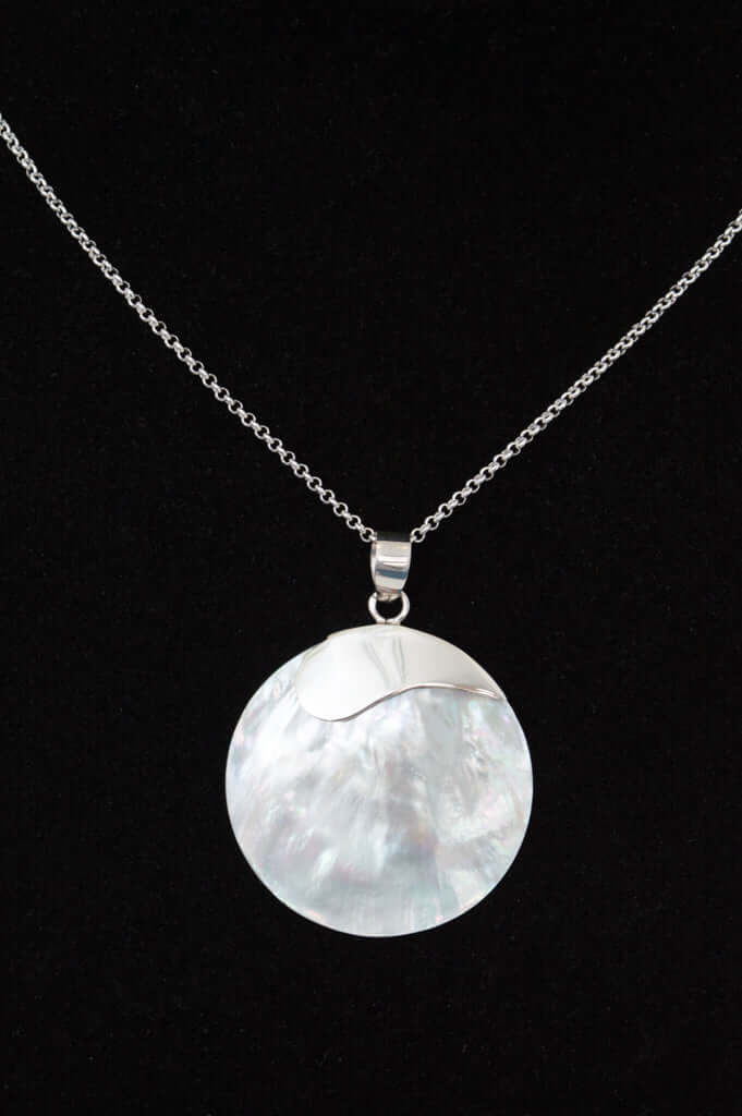 Close-up of classic 925 sterling silver necklace with a round shell pendant on black background