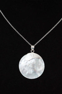 Close-up of classic 925 sterling silver necklace with a round shell pendant on black background