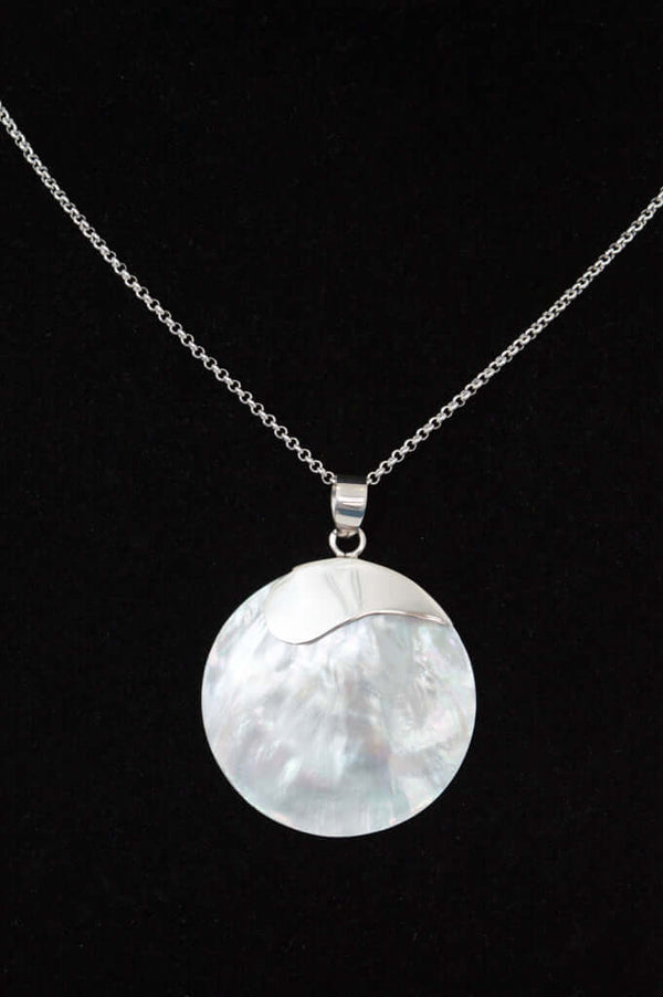 Close-up of classic 925 sterling silver necklace with a round shell pendant on black background