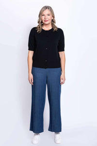 Woman facing forward in black cardigan with blue wide-leg pants and white sneakers
