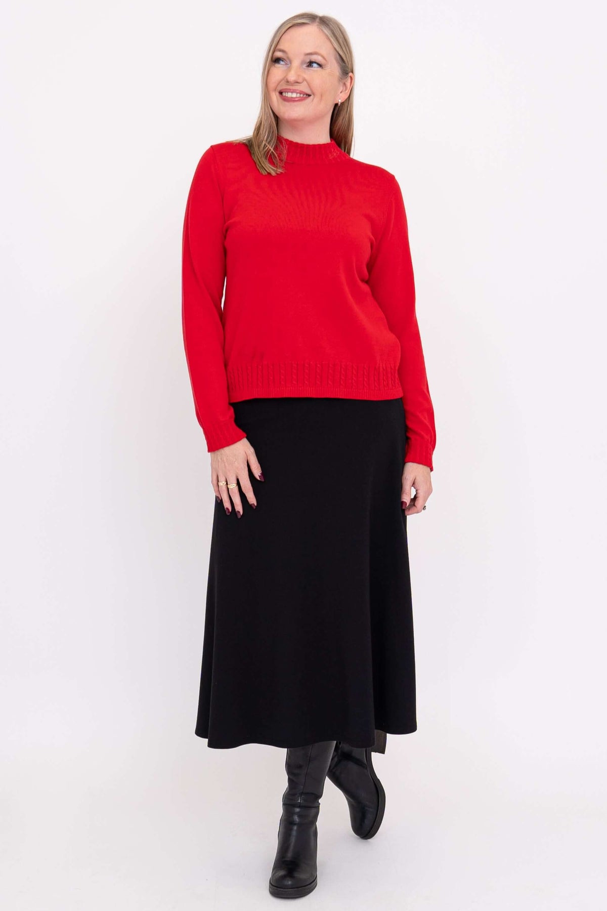 Woman standing in red mock neck sweater and black skirt, facing forward, smiling