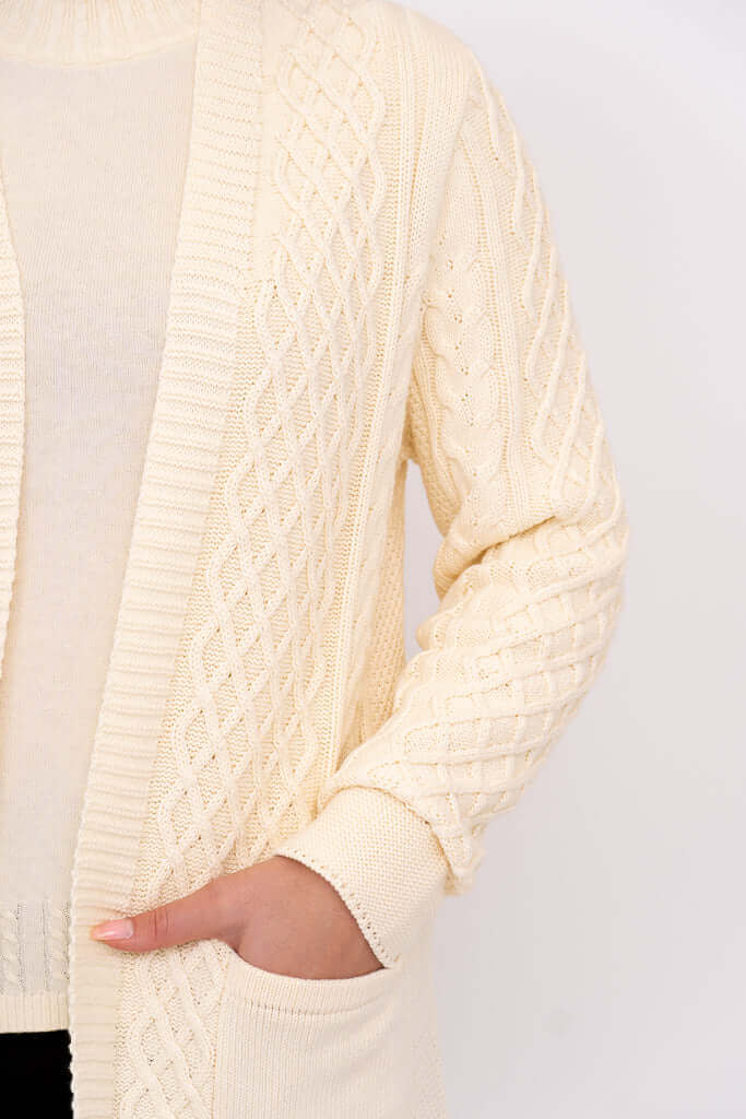 Close-up of cream cable knit cardigan texture and patch pocket detail