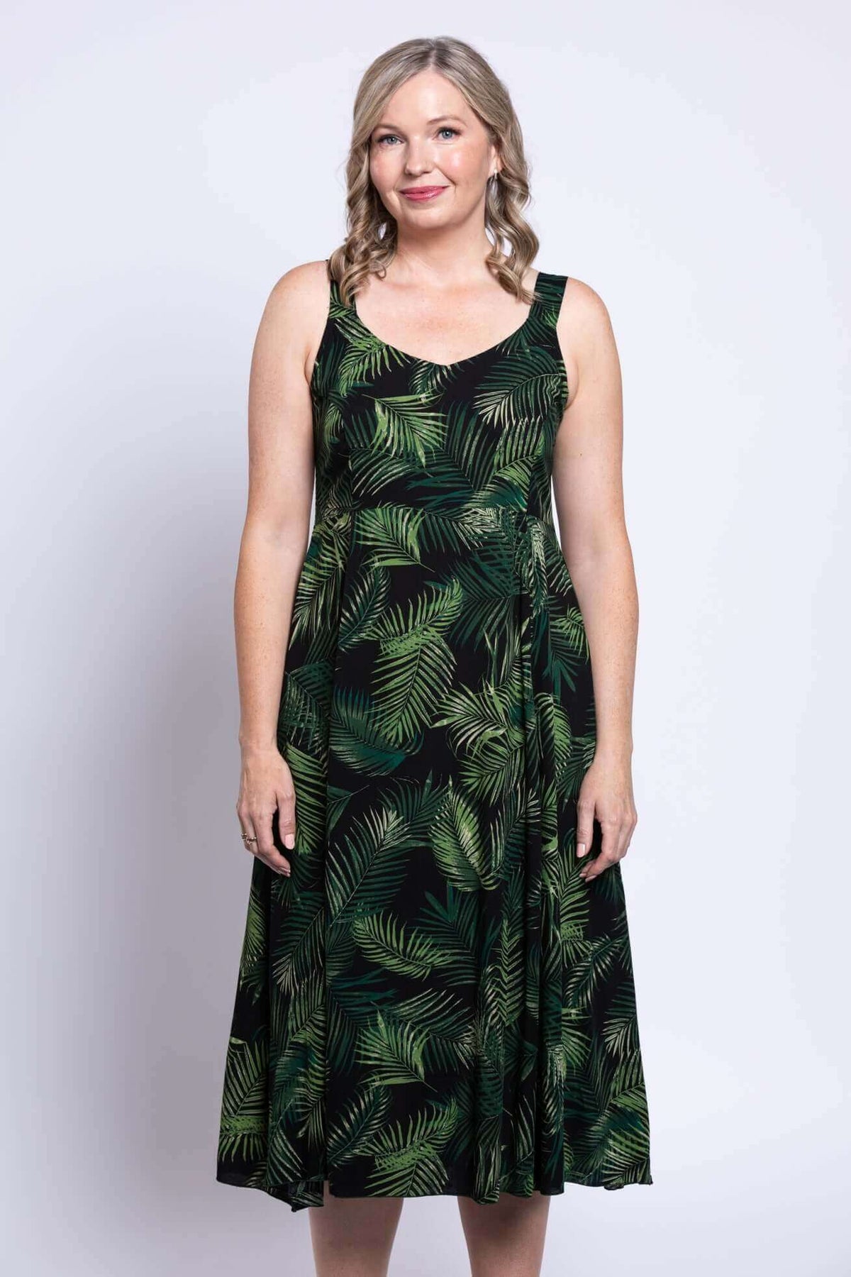 Close-up front view of a woman in a green palm leaf pattern empire waist dress