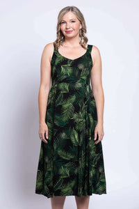Close-up front view of a woman in a green palm leaf pattern empire waist dress