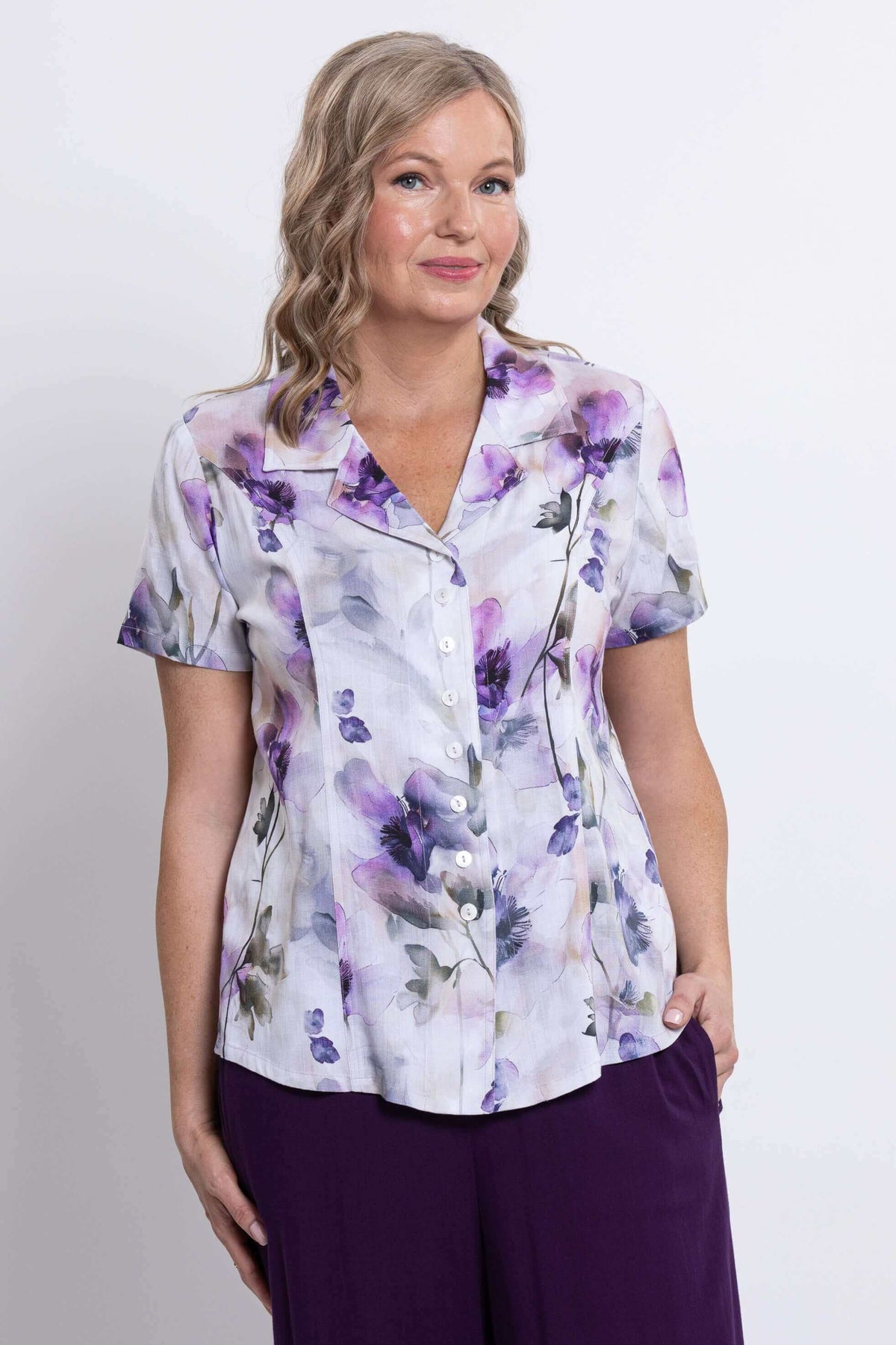 Close-up front view of a woman wearing a short sleeve floral button-up shirt