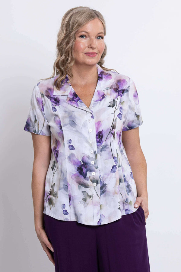 Close-up front view of a woman wearing a short sleeve floral button-up shirt
