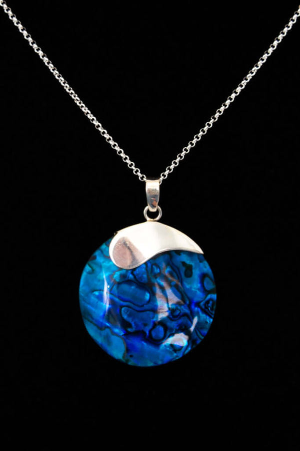 Close-up of a necklace with a round ocean-blue shell and silver pendant on a silver chain