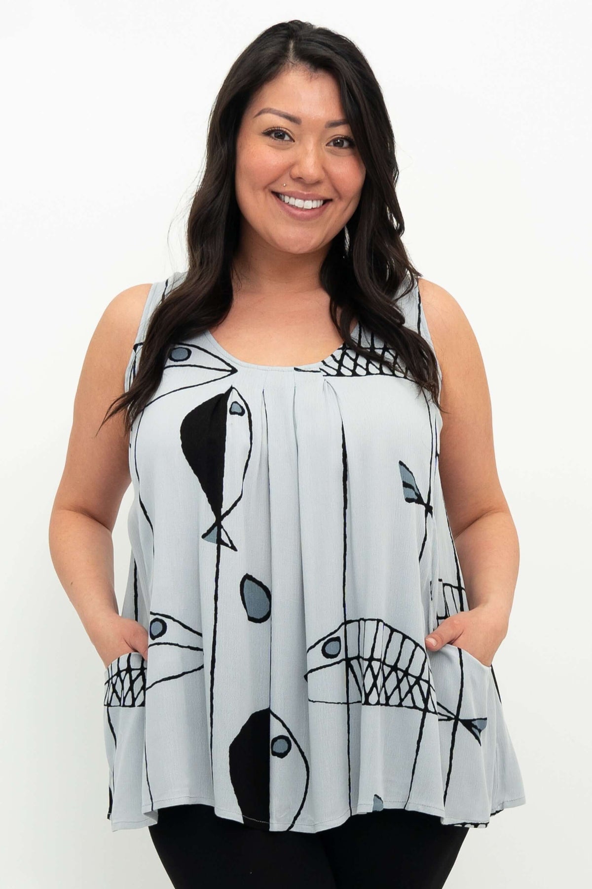 Close-up of model wearing light blue sleeveless pleated tank top with abstract fish print and pockets
