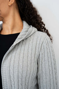 Close-up of the cable knit pattern and hood on a light grey sweater