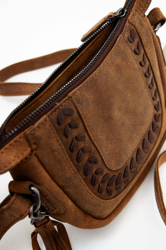 Detailed view of decorative stitching and zipper on brown leather crossbody bag