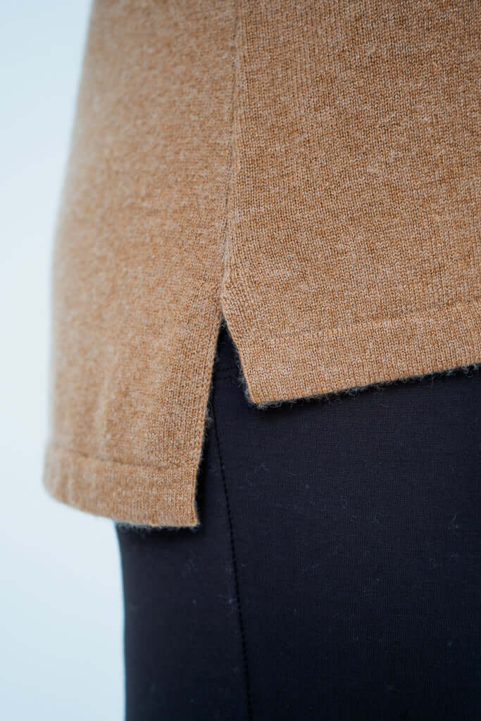 Close-up of hi-lo hemline detail on camel sweater