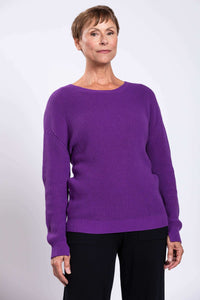 Close-up of woman in a purple textured knit sweater with ribbed hem and cuffs